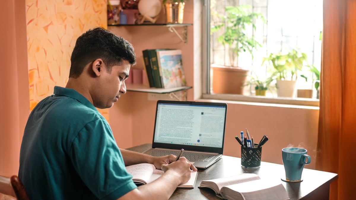 A brother taking notes as he studies the Bible. He uses the “JW Library” app on his computer and a hard-copy Bible.