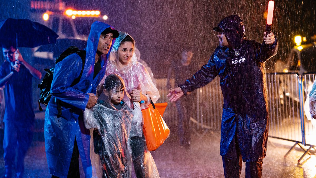 A brother, his wife, and their daughter walking through a heavy storm. They calmly follow instructions from a police officer, who is directing them to safety.