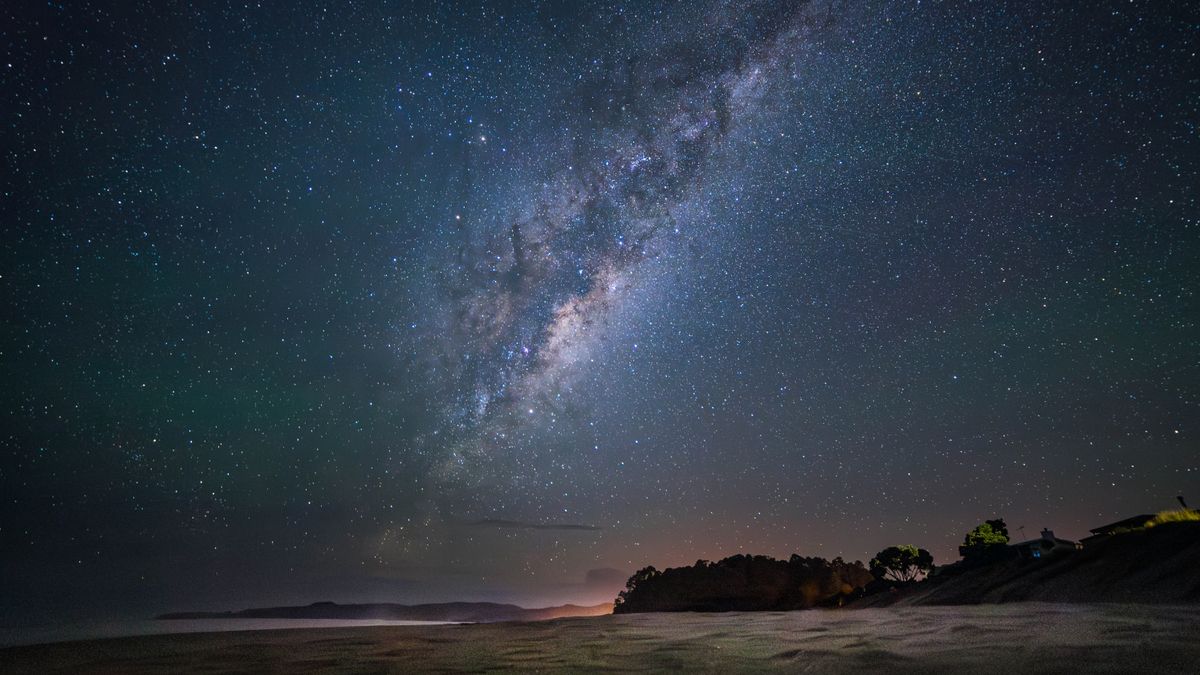 A star-filled sky over a sandy beach.