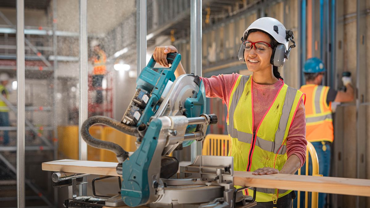 The same sister operating a large chop saw at a construction project.